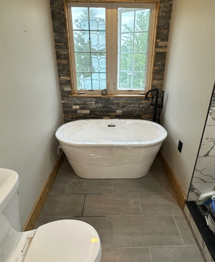 Bathroom with freestanding tub and stone feature wall